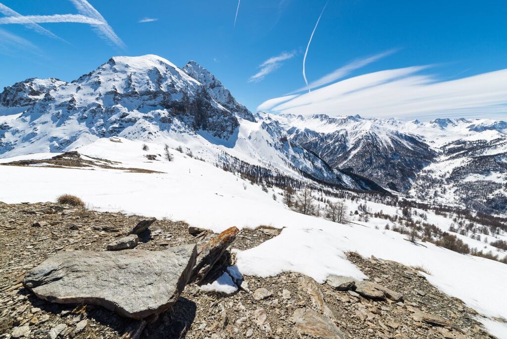 Majestic wide angle view of snowcapped high mountain peaks in the italian alpine arc, in a bright sunny day of spring, near "Via Lattea" ski resort, Torino, Italy. Boulders in the foreground.